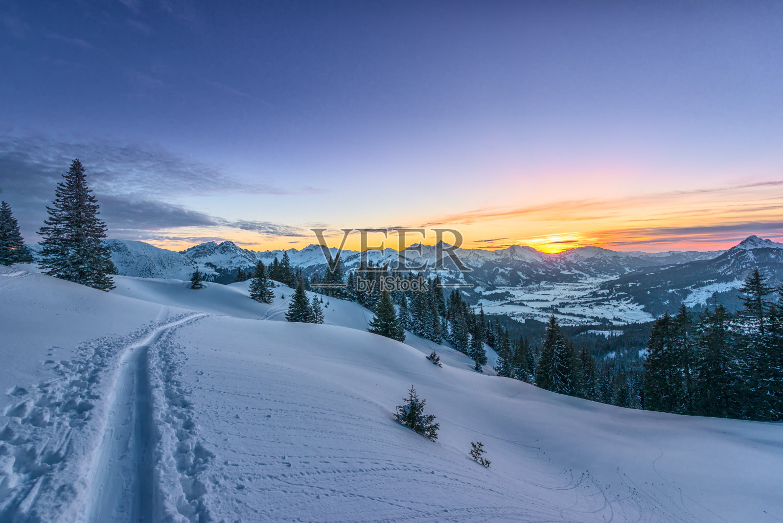 从雪原上的滑雪道上观看多彩的日落照片摄影图片