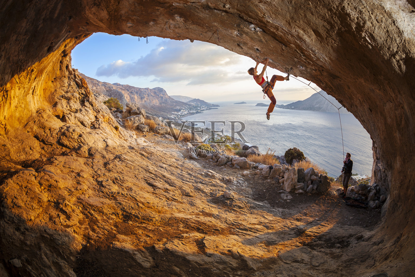 年轻女子在洞穴里领着攀岩者，男性攀岩者在确保照片摄影图片
