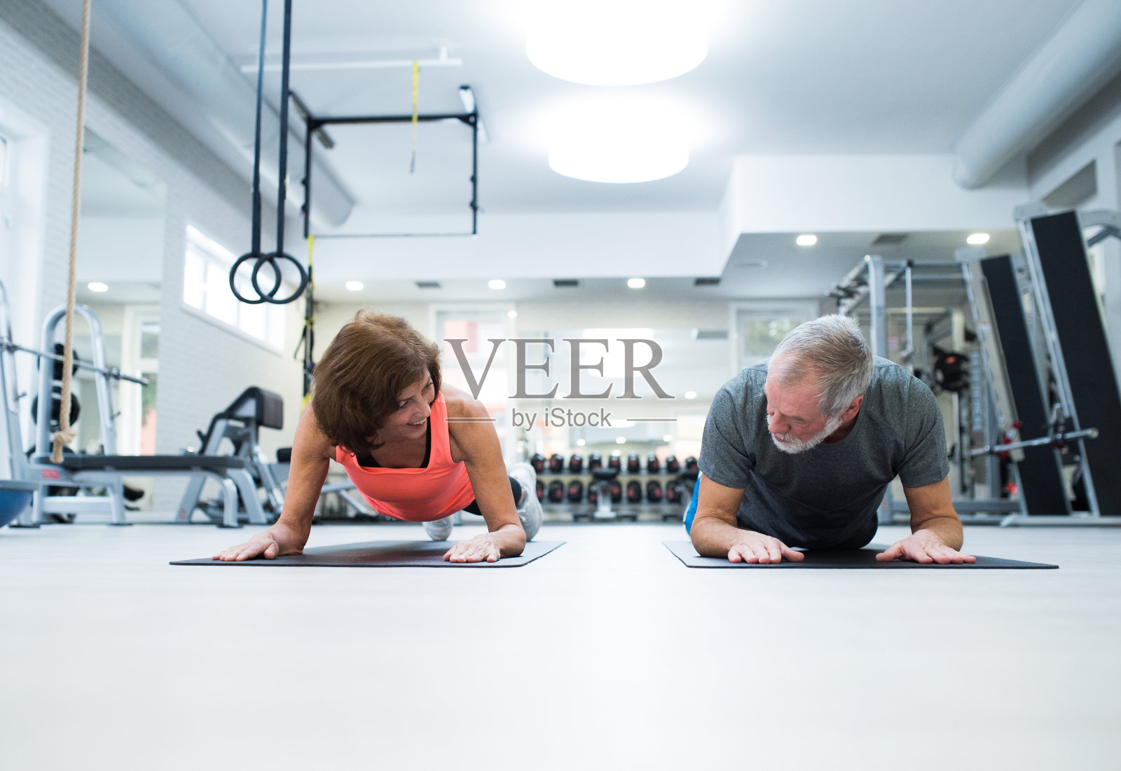 老年夫妇在健身房用平板支撑姿势锻炼腹肌照片摄影图片
