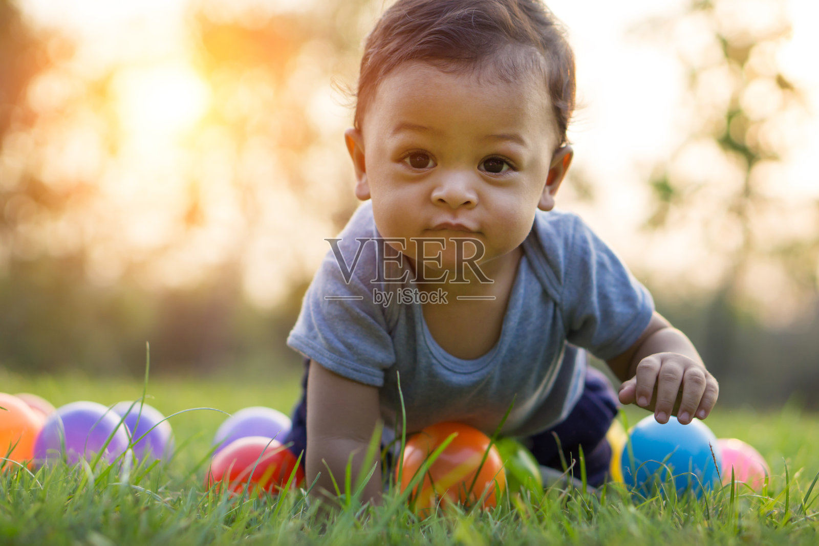 可爱的亚洲婴儿爬在草地和彩色球照片摄影图片