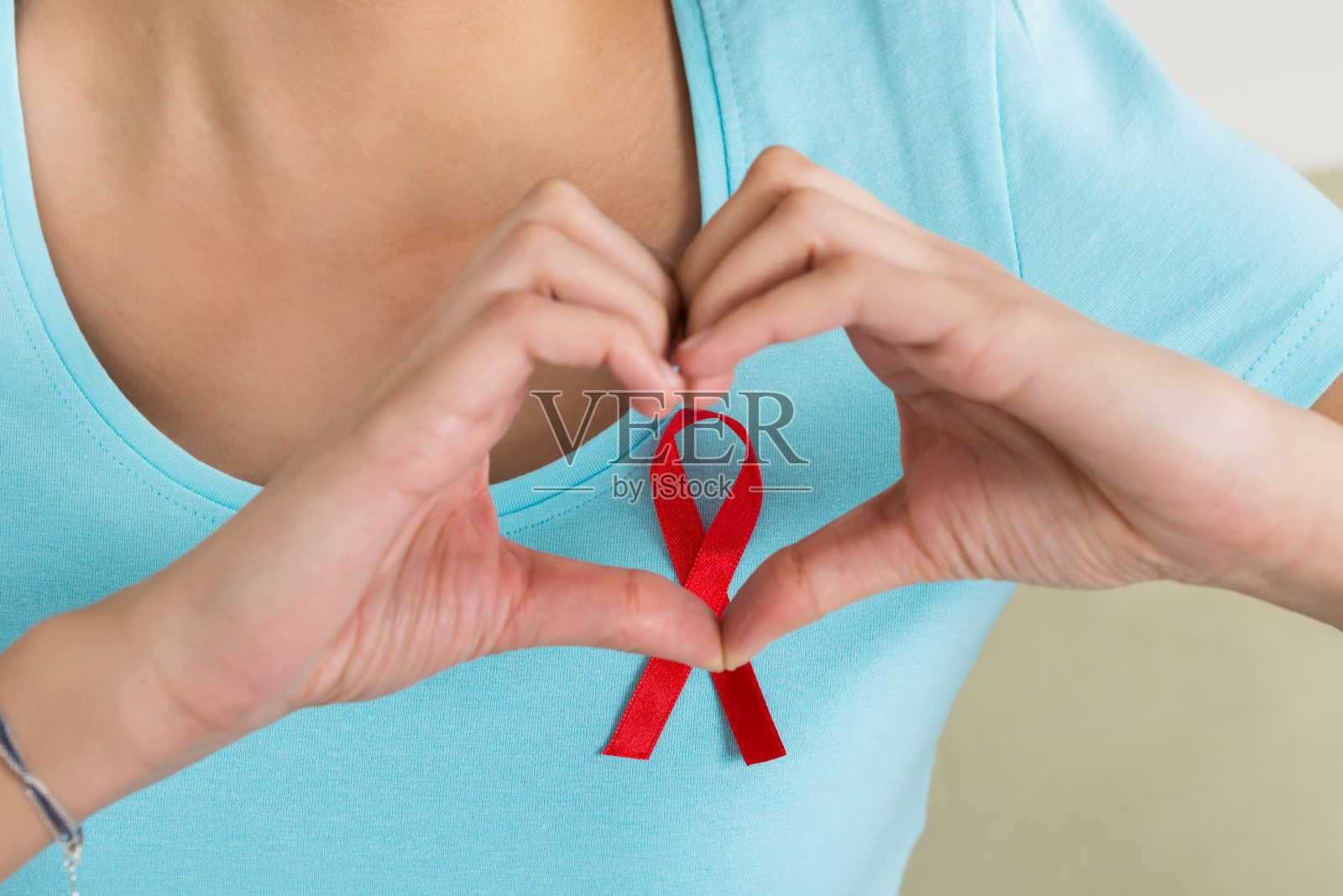 一名妇女在艾滋病意识丝带前制作心形照片摄影图片