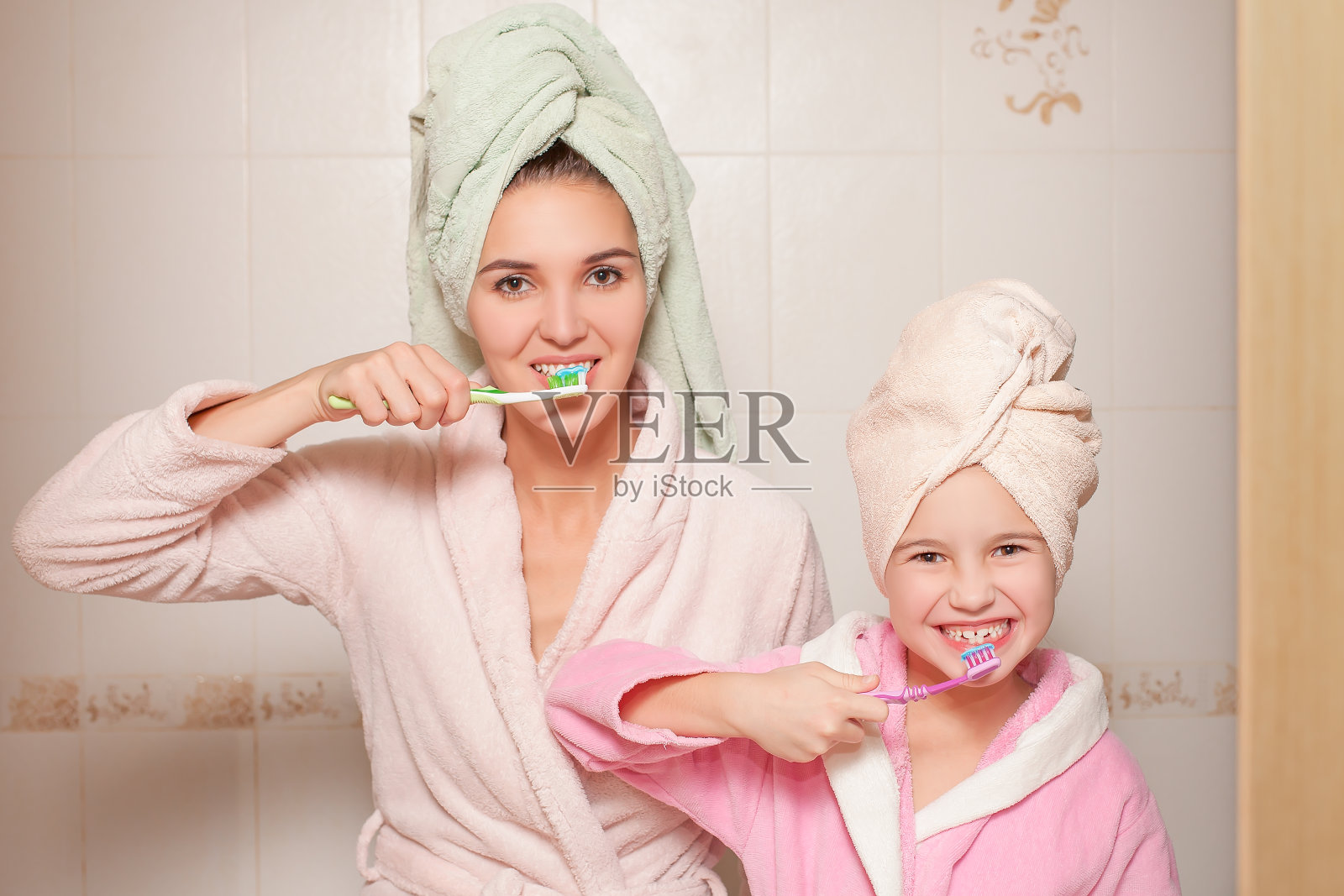 妈妈和小女儿拿着牙刷。照片摄影图片