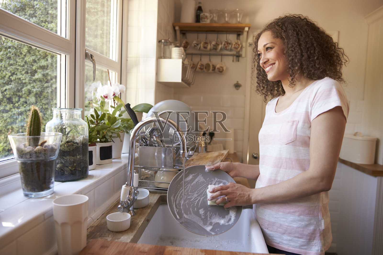 站在厨房水槽边洗碗的女人照片摄影图片