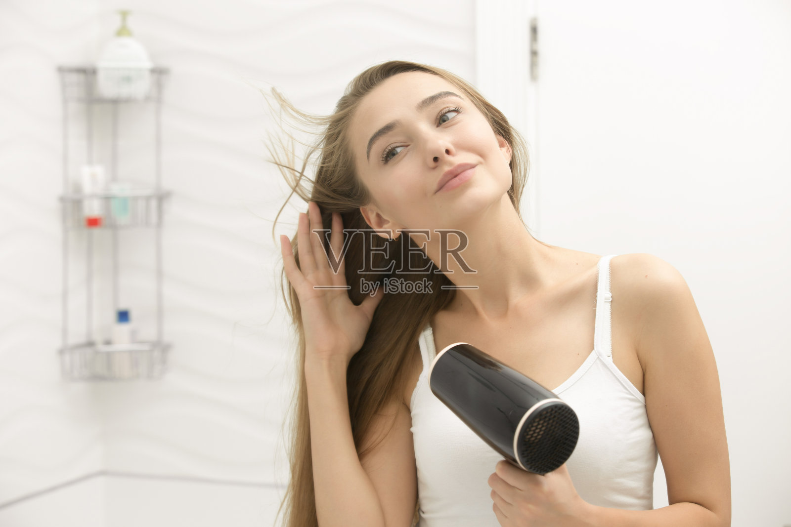 漂亮的年轻女子看着镜子在擦头发照片摄影图片