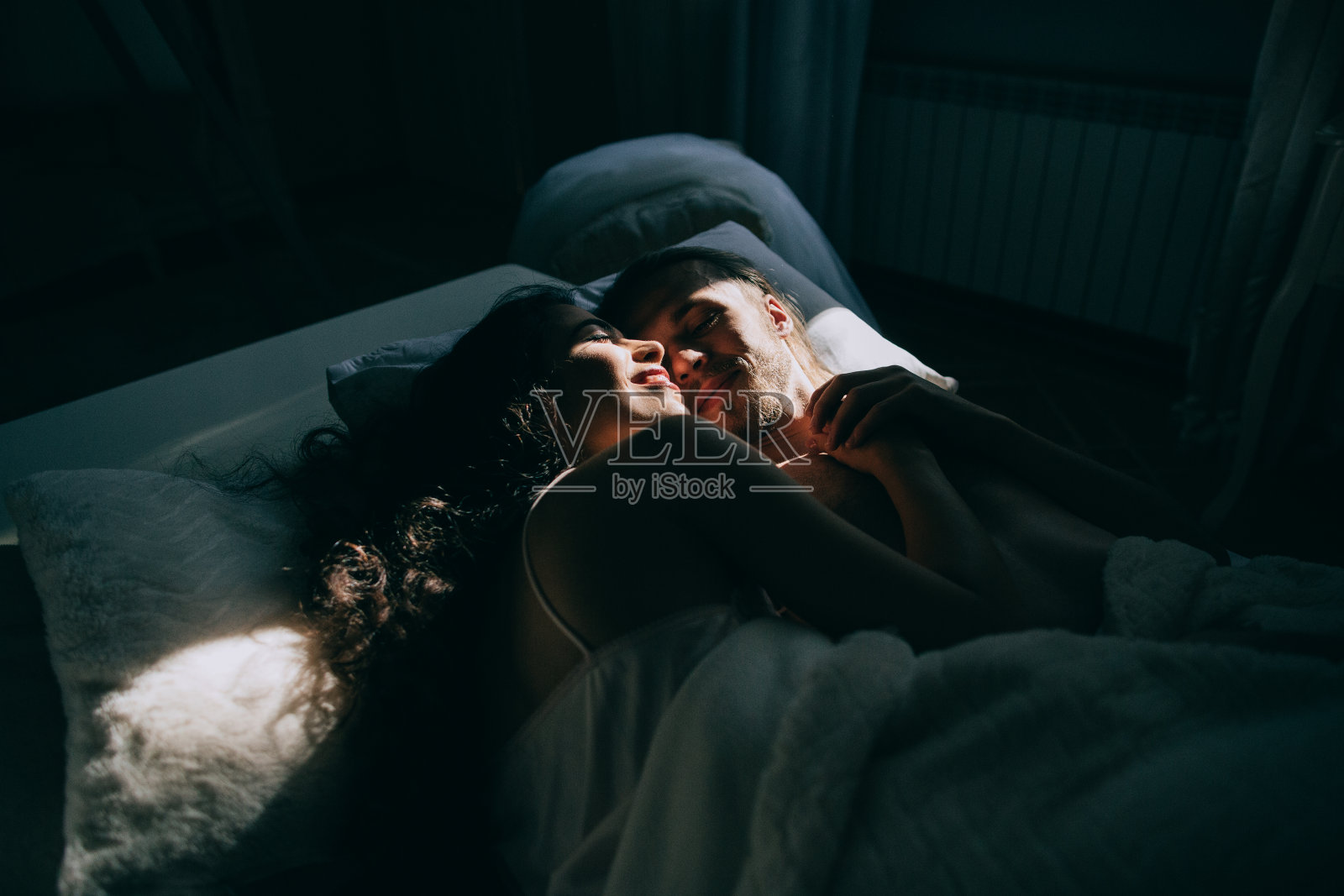 幸福的新娘和新郎拥抱和亲吻在床上照片摄影图片