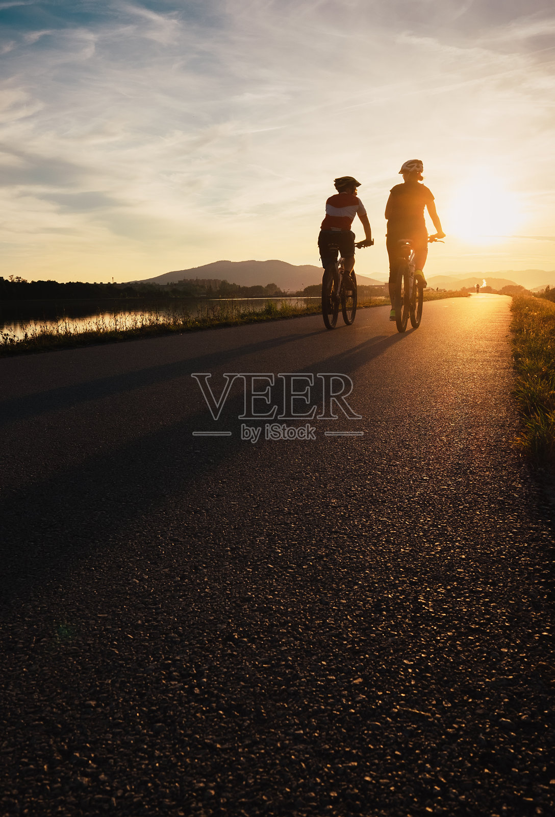 两个骑自行车的人在日落大道上照片摄影图片