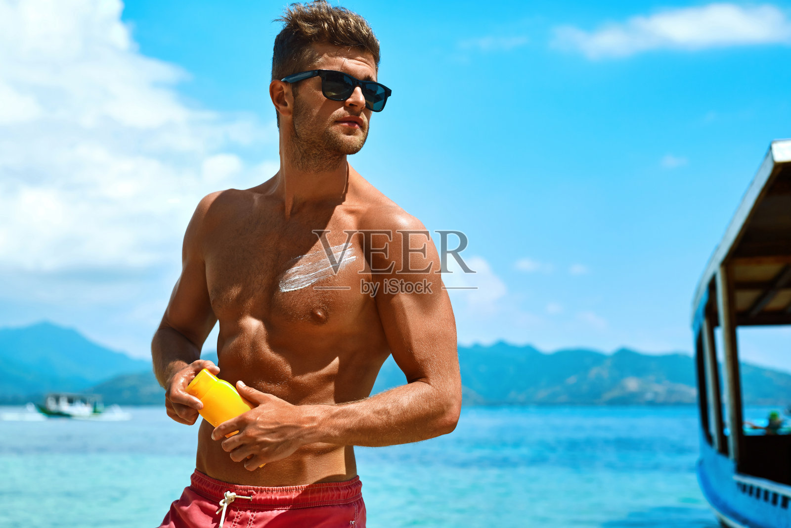 夏日沙滩上使用防晒霜的男士晒黑照片摄影图片