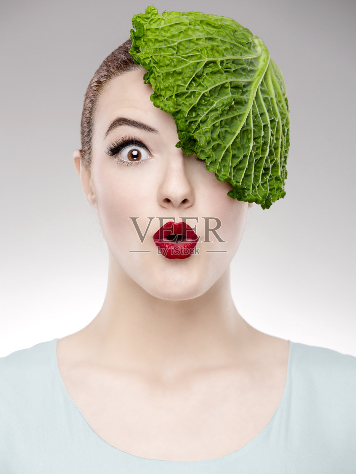 这是一个女人的肖像，她头上顶着一颗卷心菜，说明了素食主义的概念照片摄影图片