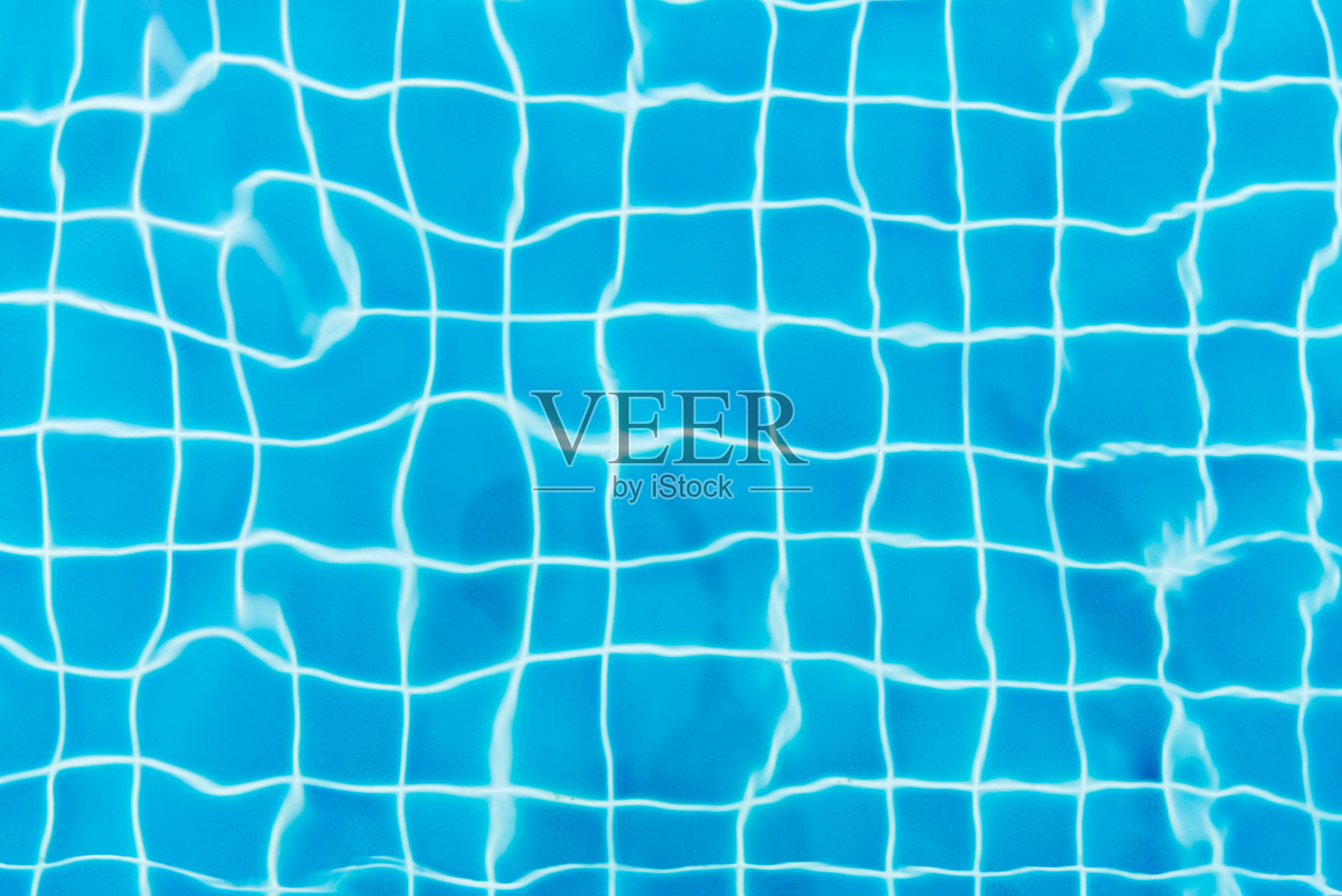 蓝色瓷砖游泳池背景上的水波。从以上观点。照片摄影图片