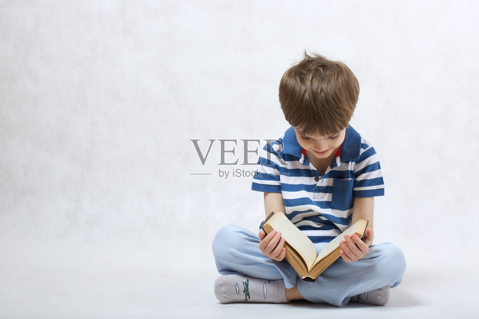 男孩正在看一本书，背景是白色的照片摄影图片