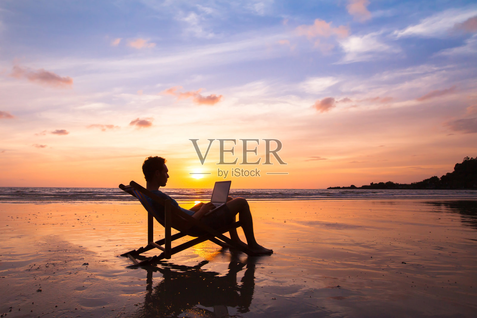 一个在海滩上用笔记本电脑工作的商人照片摄影图片