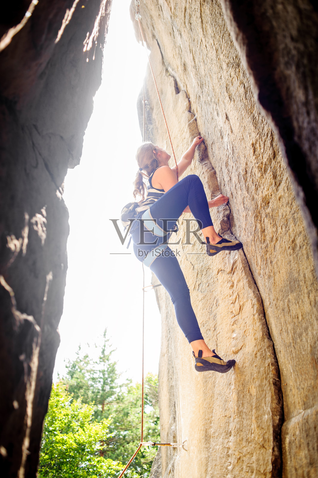 女性攀登者用绳子在岩壁上攀爬照片摄影图片