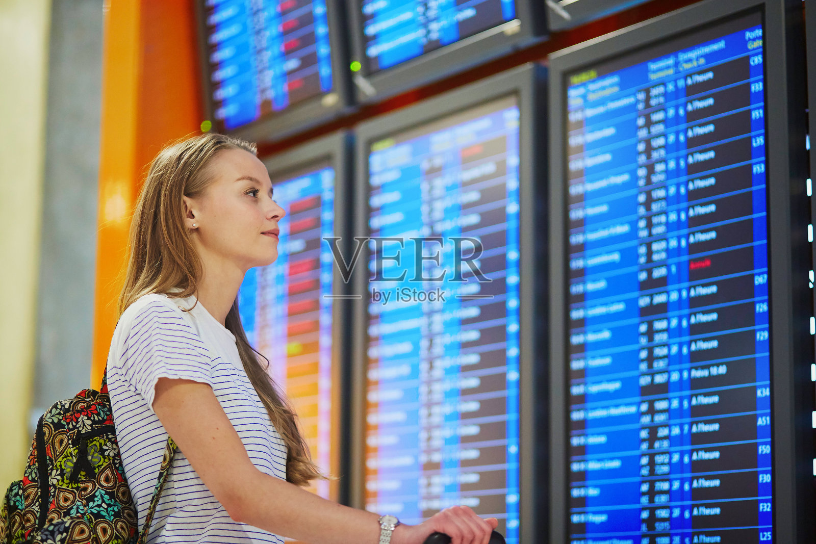 一位年轻女子在机场看航班信息板照片摄影图片