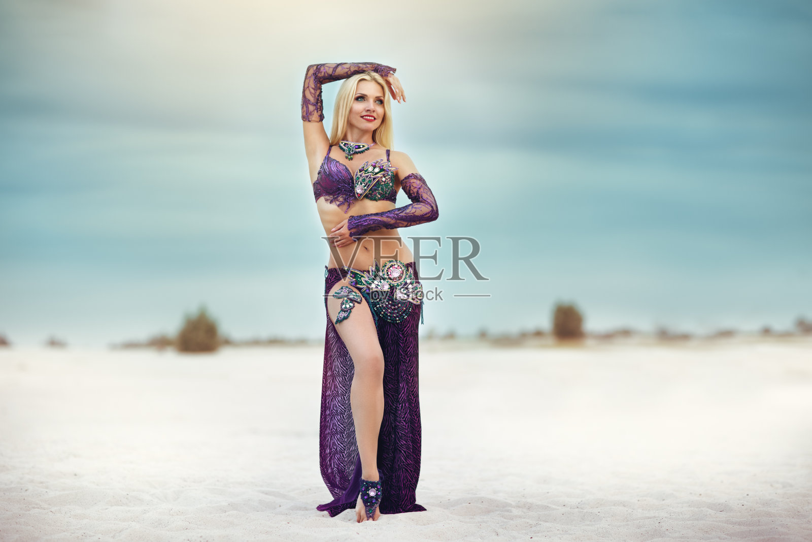 美丽的微笑女士跳舞肚皮舞在沙子沙漠照片摄影图片