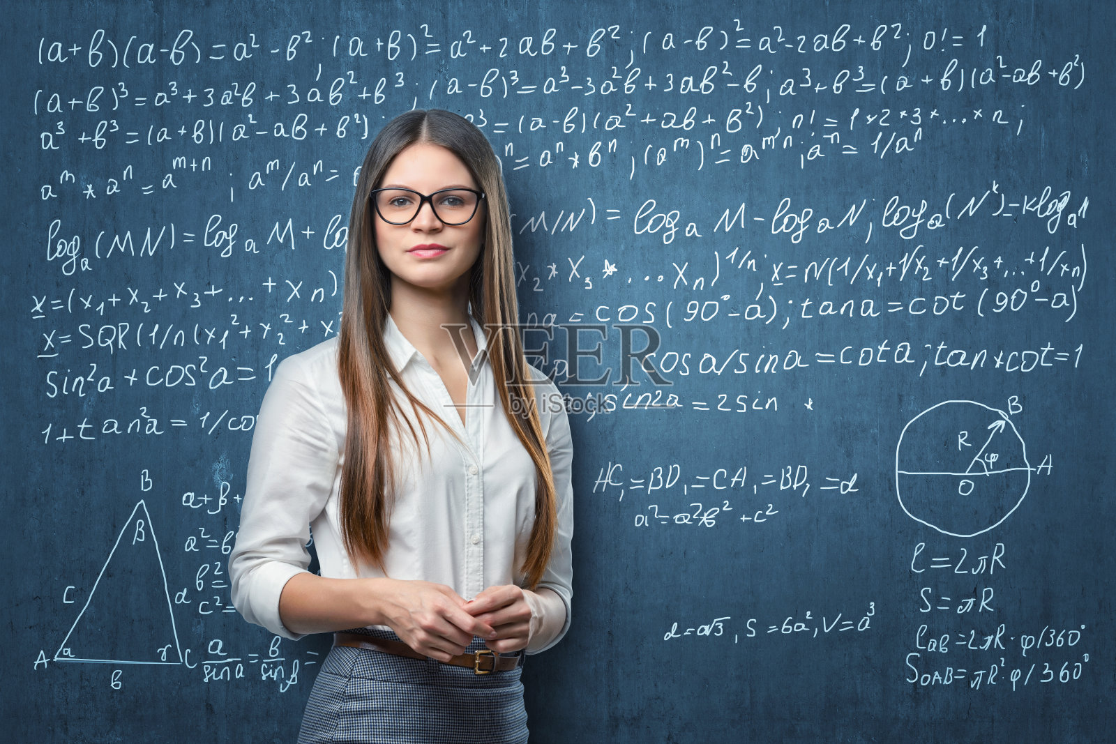 年轻的女商人站在黑板的背景上写着数学照片摄影图片