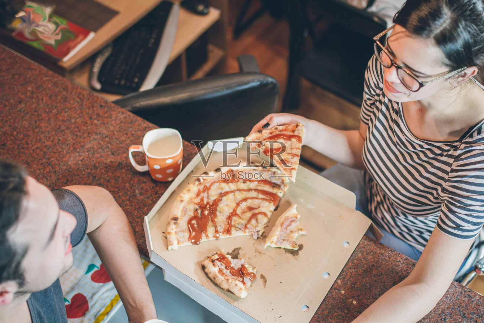 一对快乐的年轻夫妇在厨房吃披萨照片摄影图片