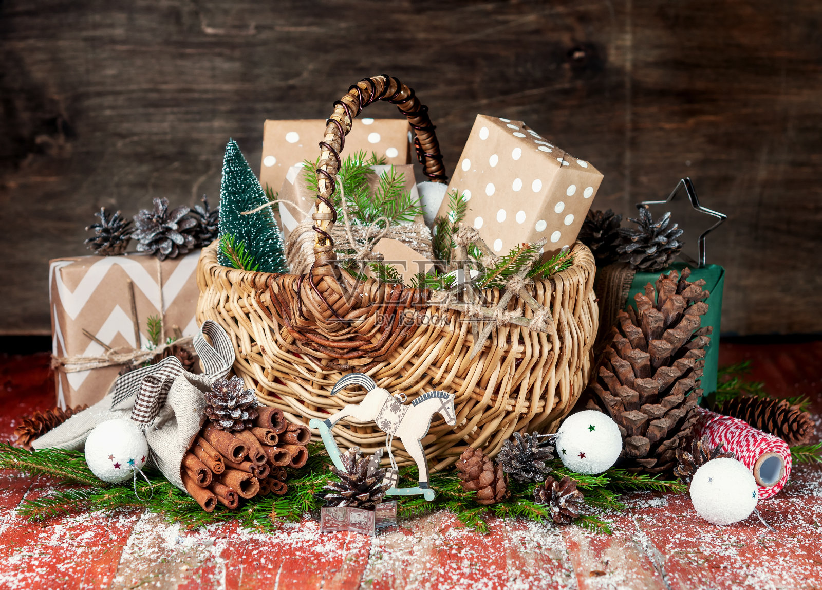 装有礼物的圣诞篮子。云杉的树枝和球果。包里有肉桂。照片摄影图片