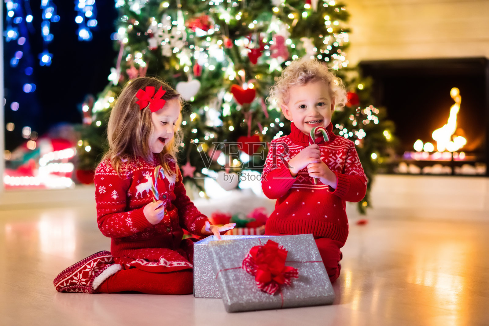 孩子们在圣诞树下，在美丽的客厅照片摄影图片