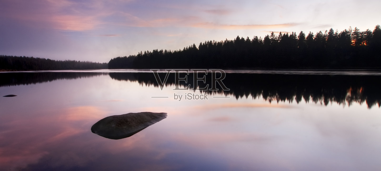 黎明时分宁静的湖面上有一块石头照片摄影图片