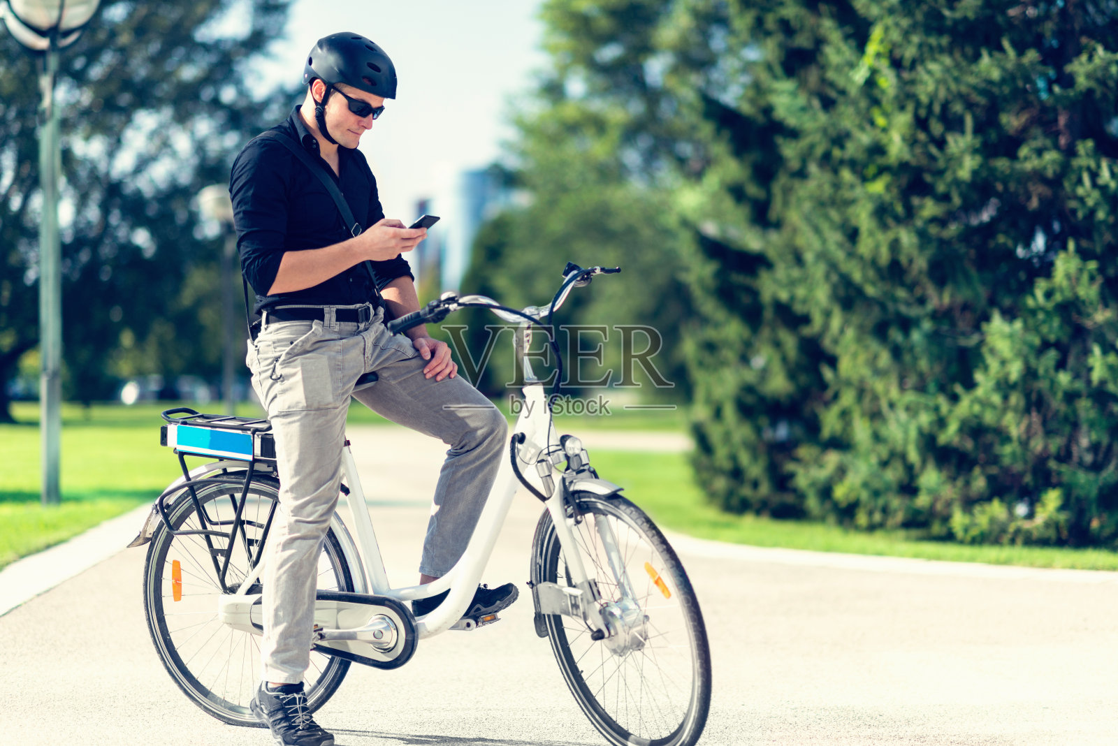 城市年轻人用电动自行车，用智能手机照片摄影图片