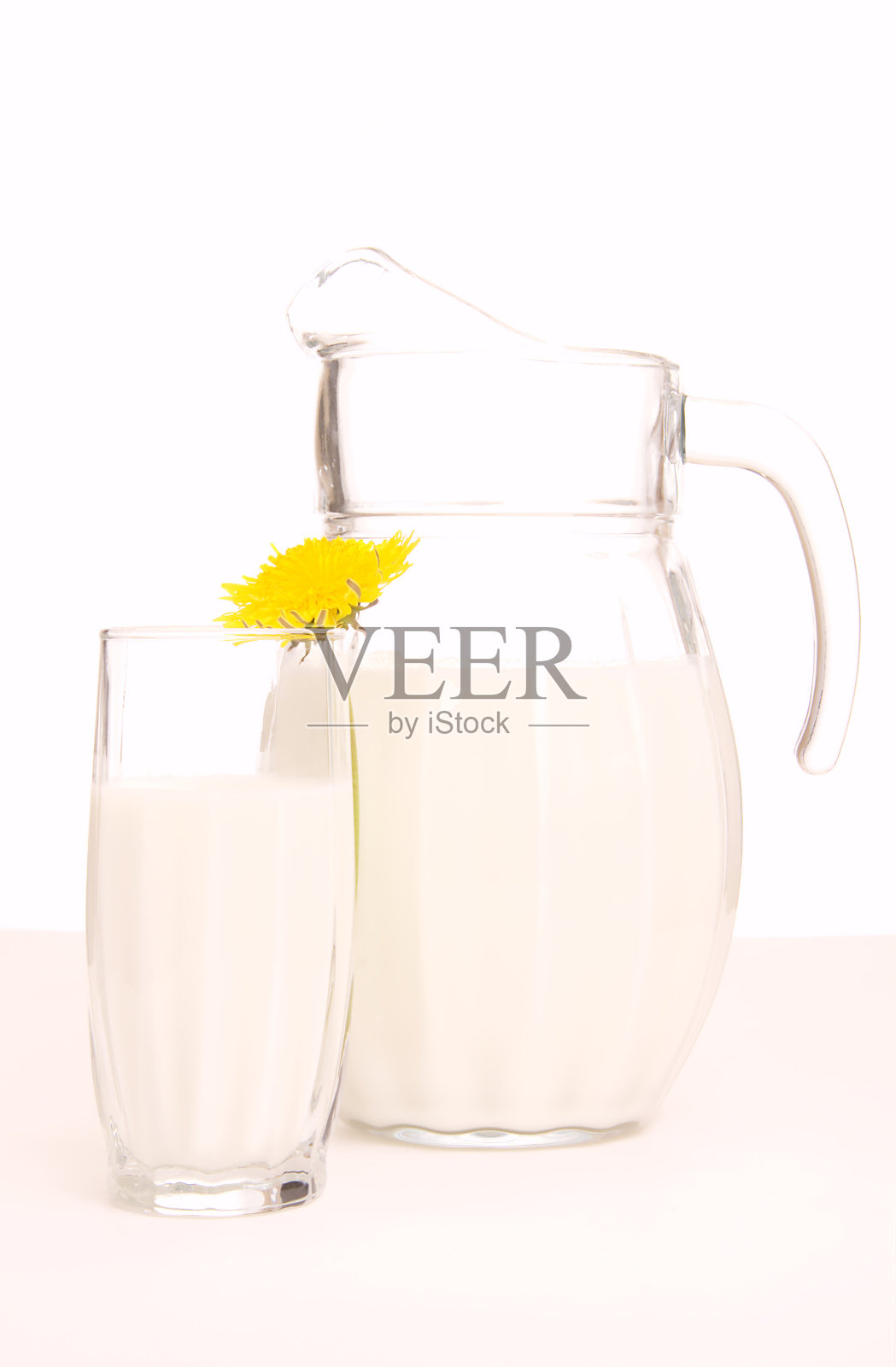 装着新鲜牛奶和黄色花朵的玻璃壶照片摄影图片