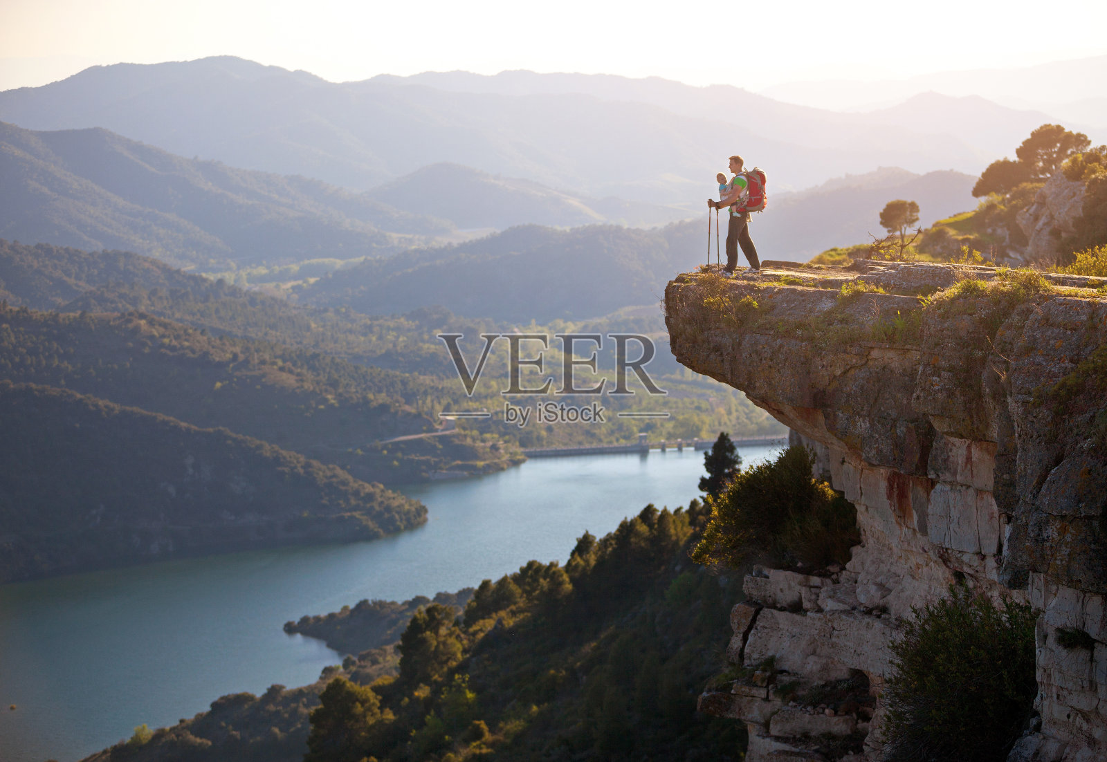 带着孩子的徒步旅行者站在悬崖上欣赏山谷景色照片摄影图片