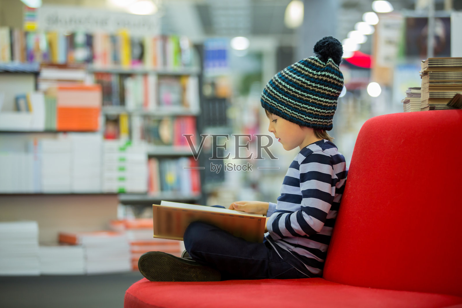 可爱的小男孩，坐在书店里照片摄影图片