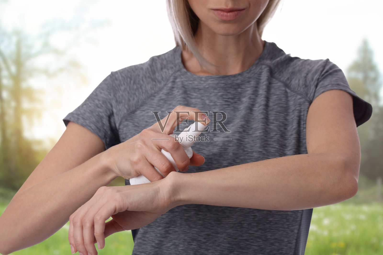 女人在室外的皮肤上喷洒杀虫剂照片摄影图片