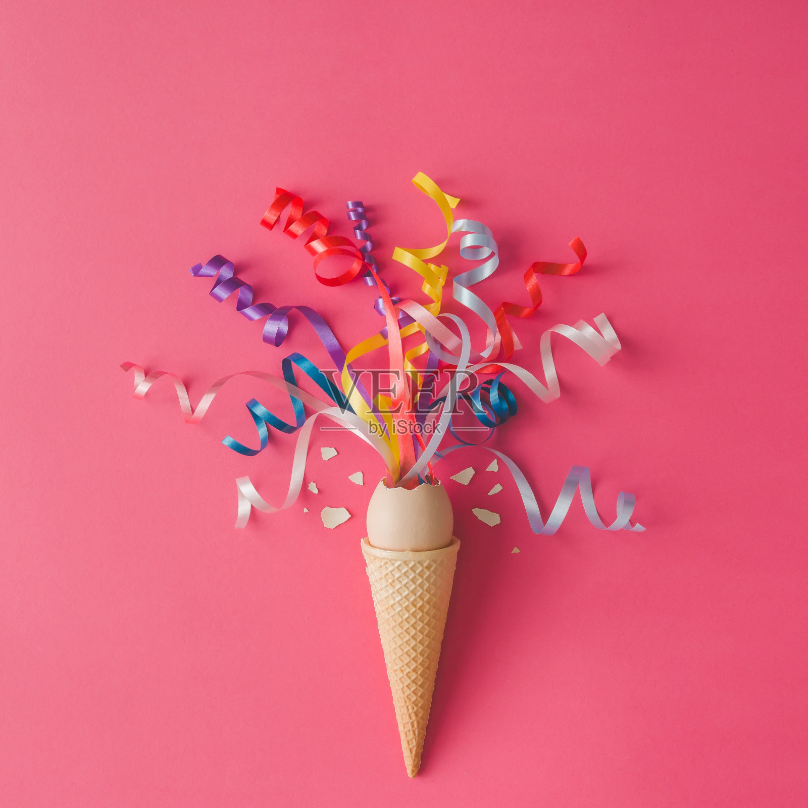 蛋筒冰淇淋，粉红色背景上有派对彩带。最小的食品的概念。平的。照片摄影图片