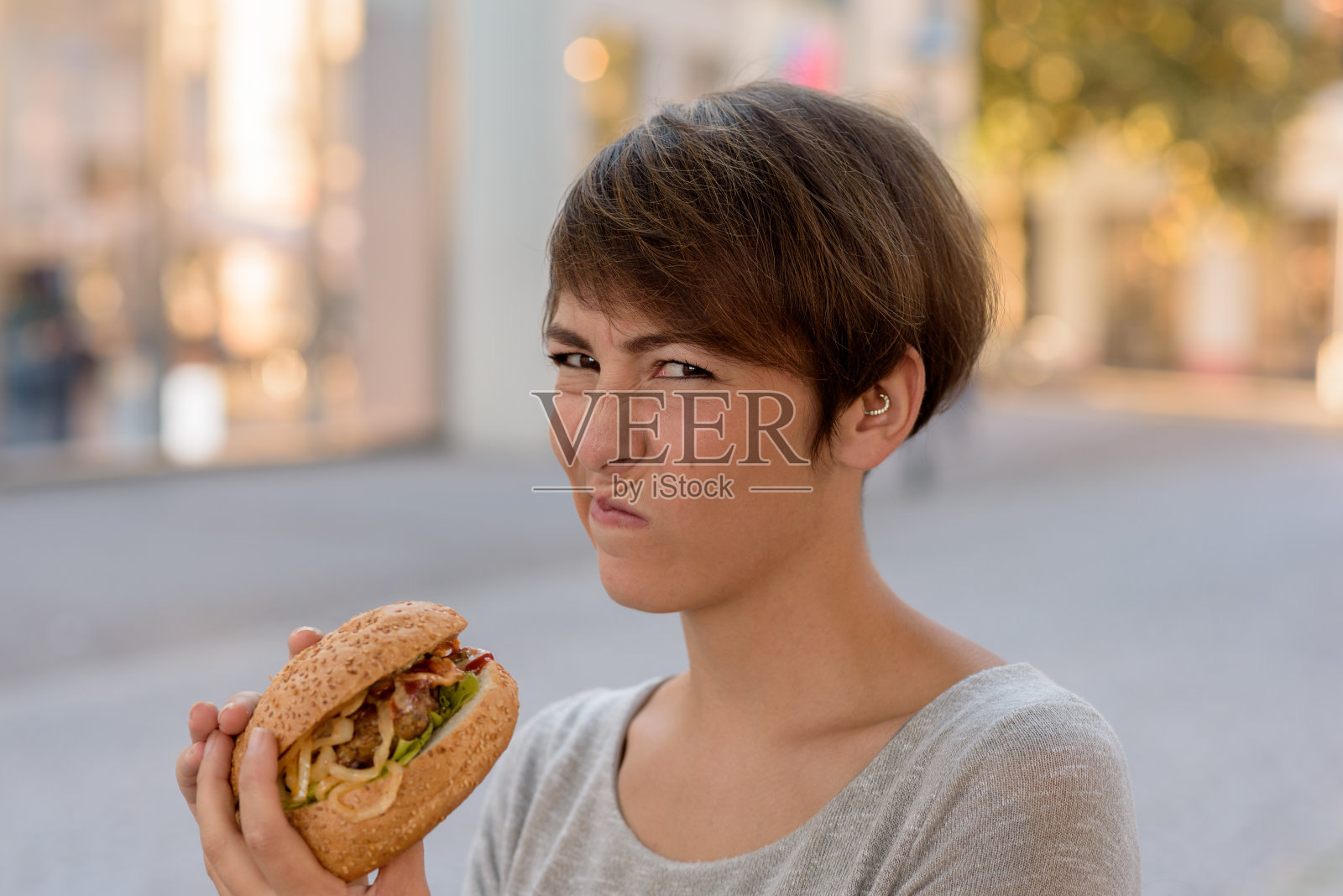 一个年轻女子在汉堡前做着厌恶的鬼脸照片摄影图片