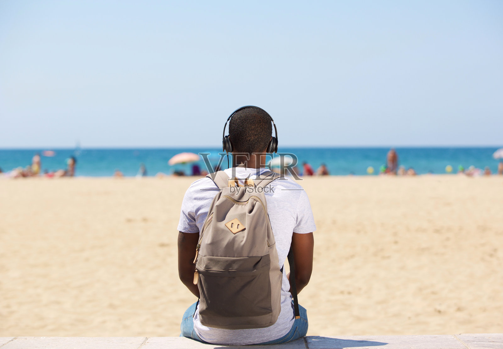 男人坐在海滩边戴着耳机听音乐照片摄影图片