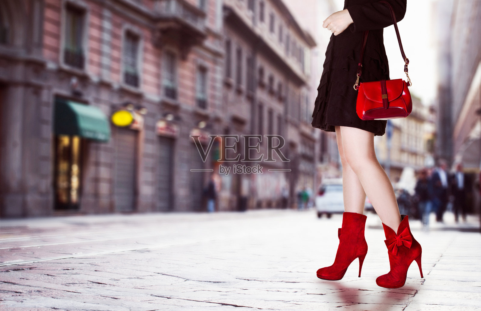 女孩穿着红色的包和红色的靴子在街上。照片摄影图片