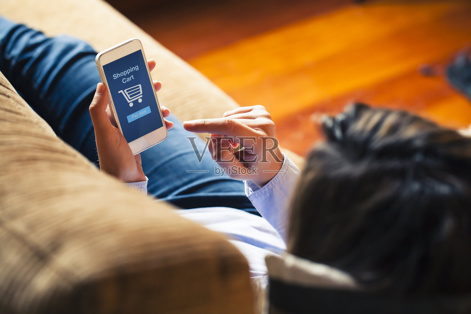 女人躺在家里用手机购物。蓝色屏幕。照片摄影图片