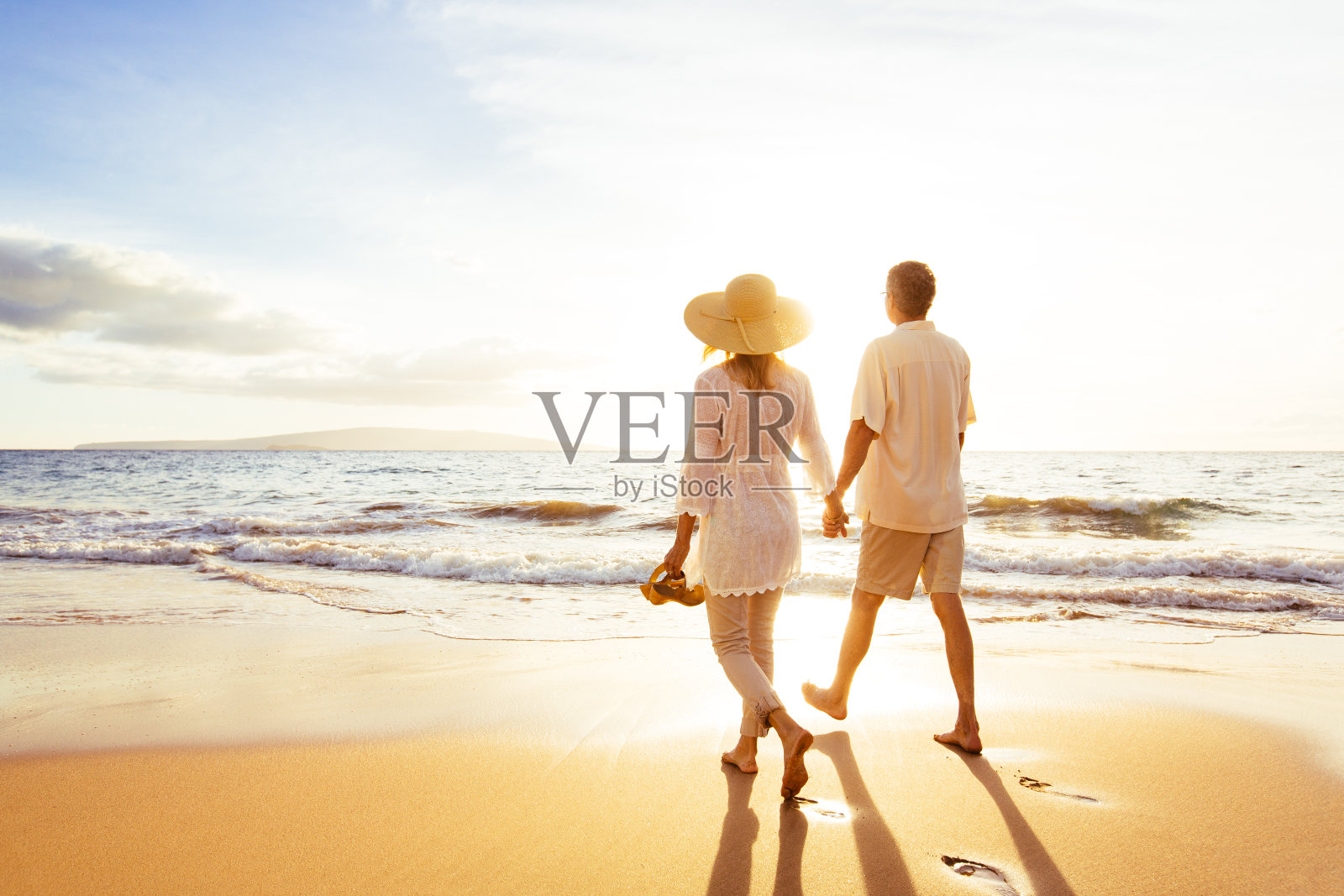 一对成熟的夫妇在日落的海滩上散步照片摄影图片