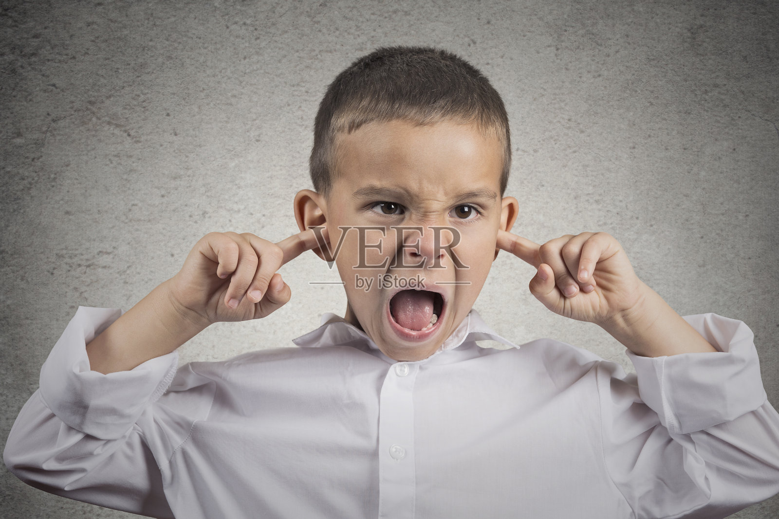 愤怒愤怒的男孩用手指堵住耳朵照片摄影图片