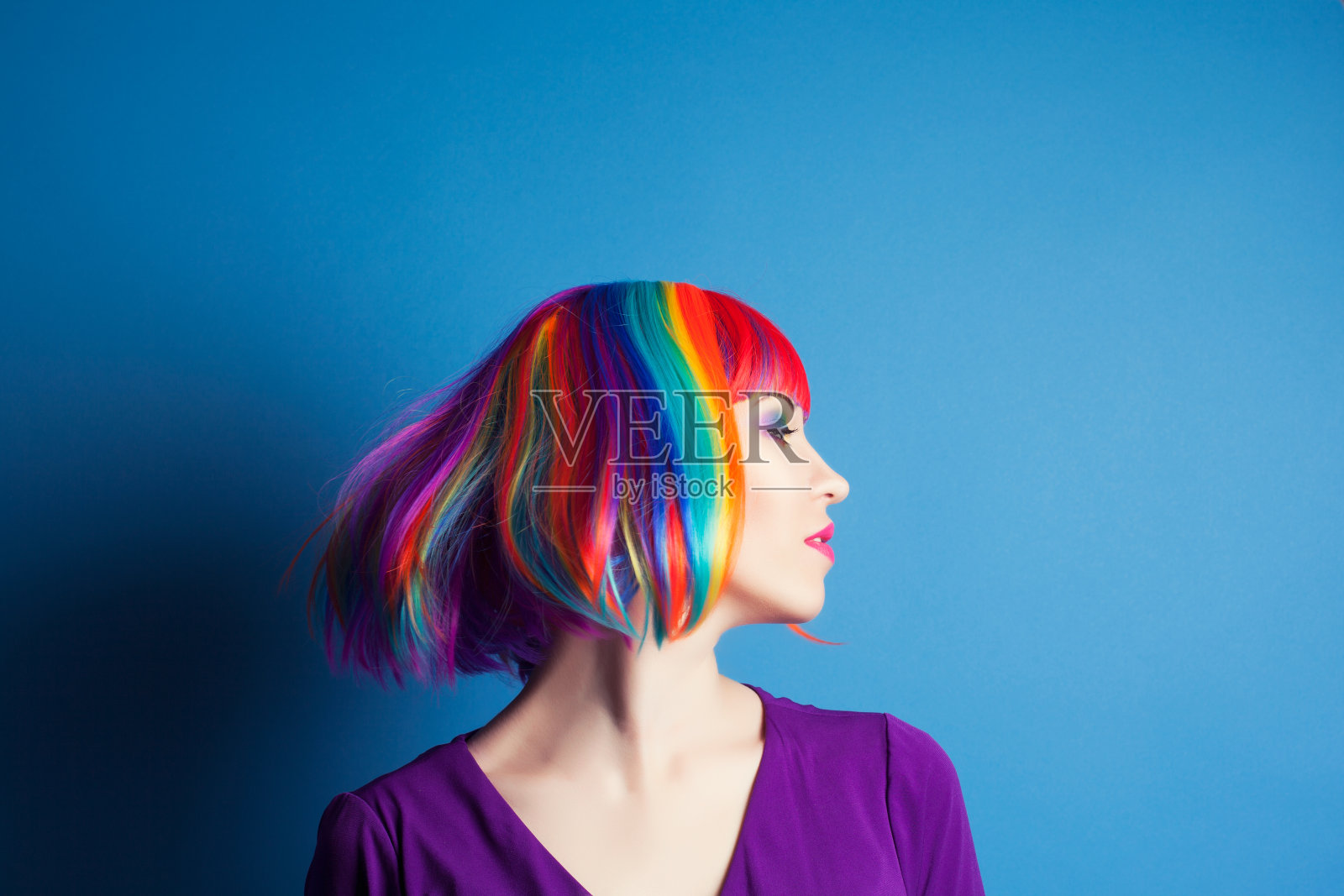 美丽的女人戴着彩色的假发在蓝色的背景照片摄影图片