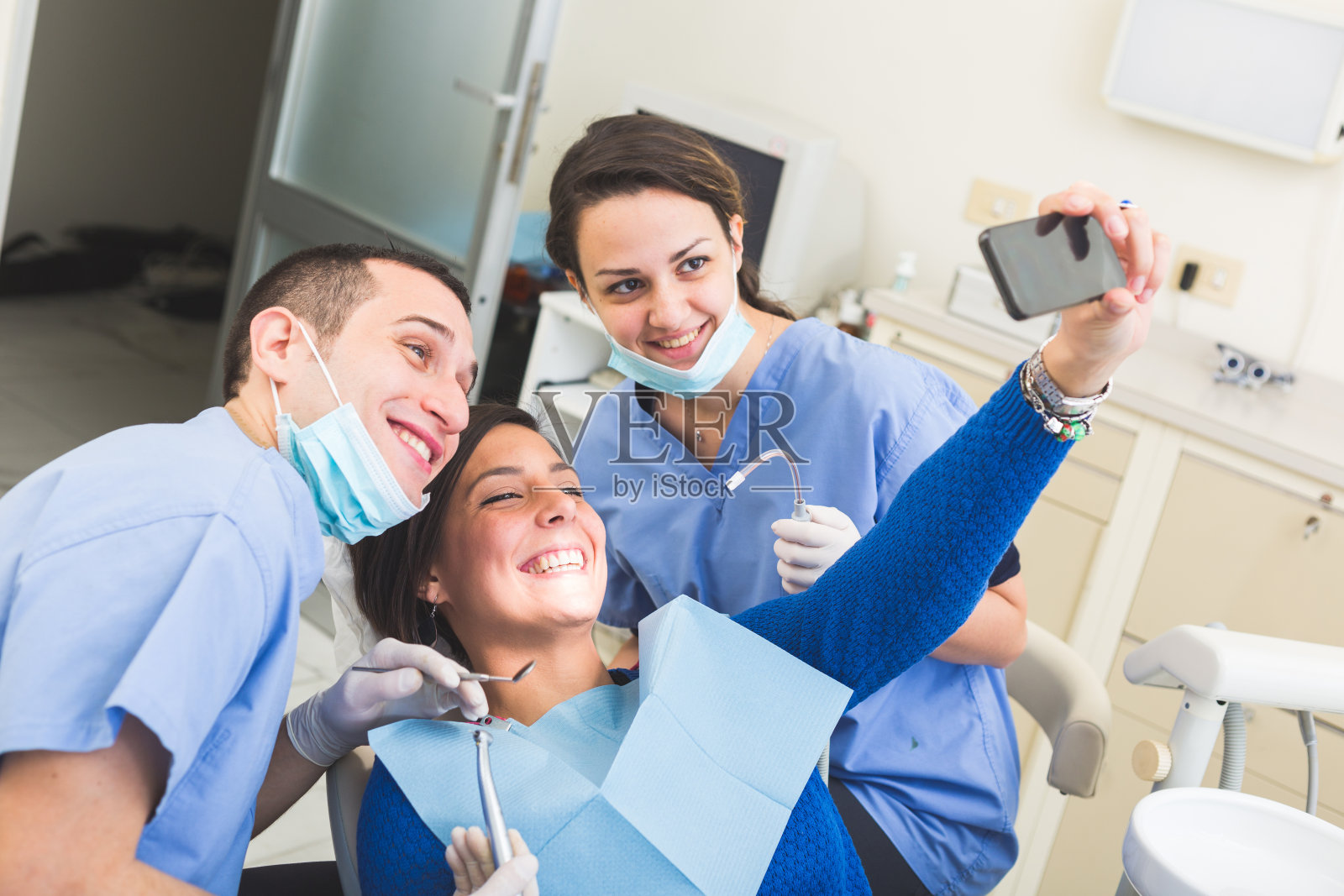 快乐的病人、牙医和助理一起自拍。照片摄影图片