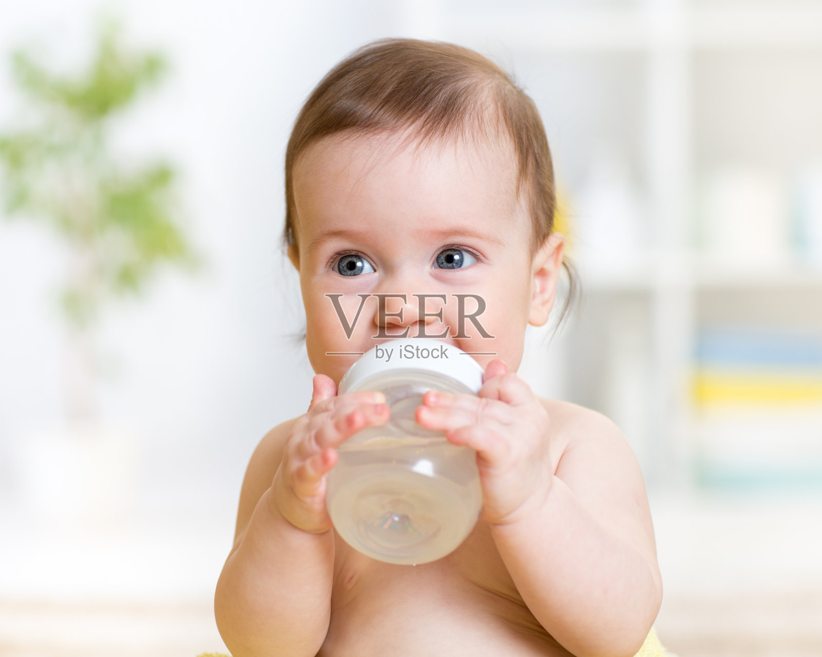 抱着奶瓶喝着水的可爱宝宝照片摄影图片