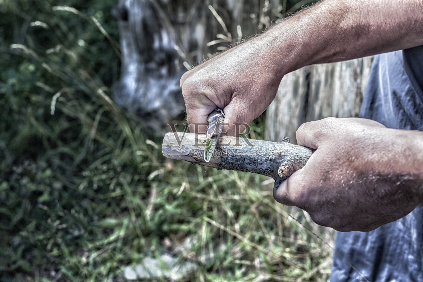 男子用削刀雕刻木棍照片摄影图片