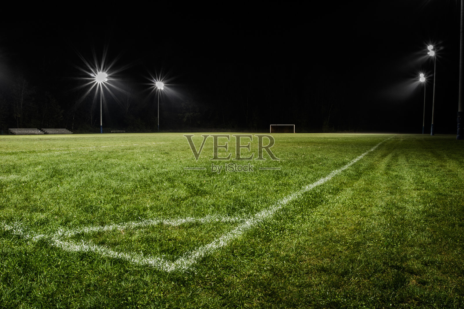在球场灯光下的夜晚，低视野的空旷足球场。照片摄影图片