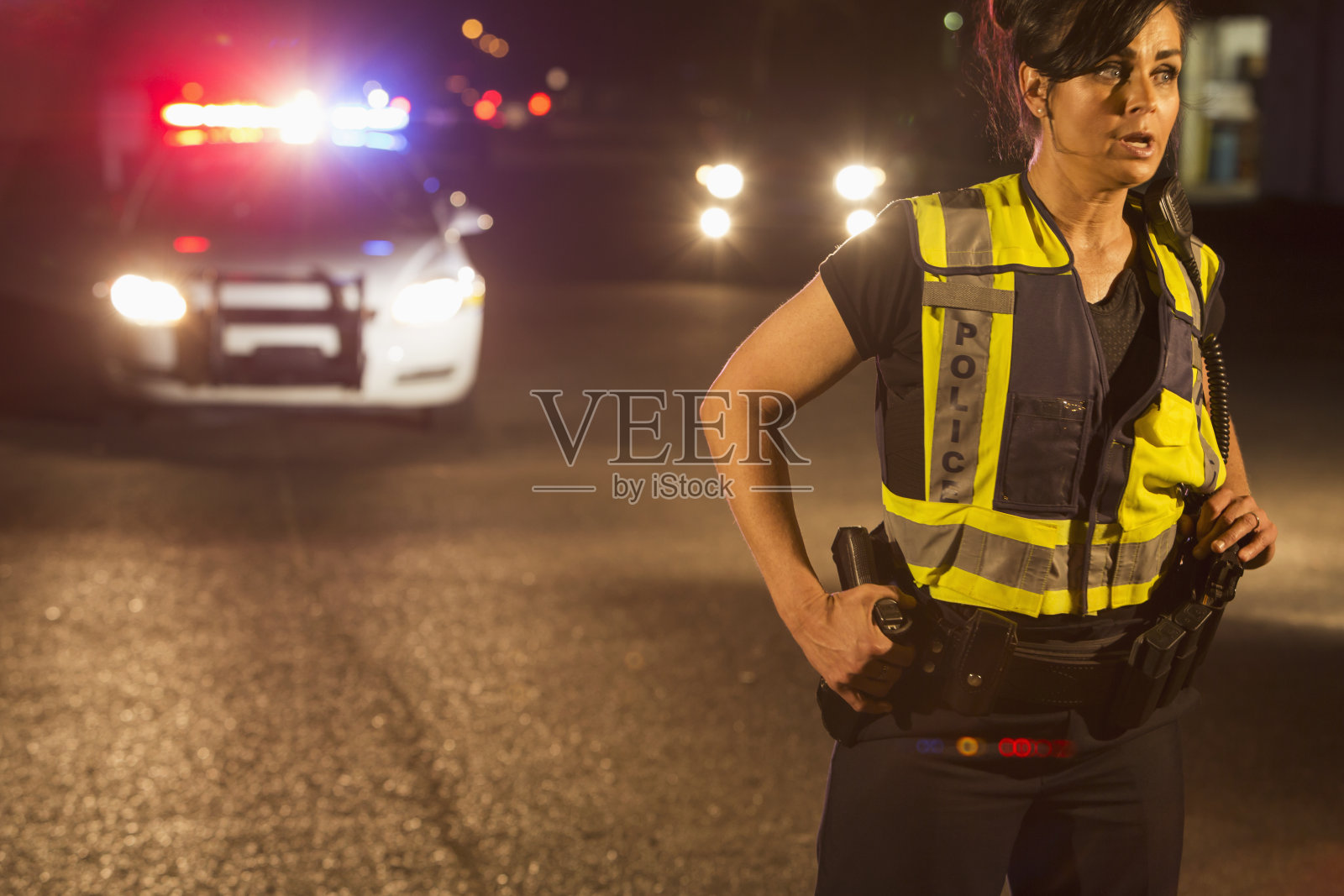 晚上有女警察在街上巡逻，后面是警车照片摄影图片