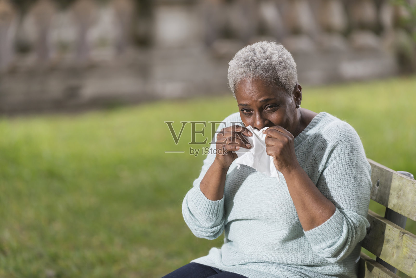 年长的黑人妇女用纸巾捂住鼻子照片摄影图片