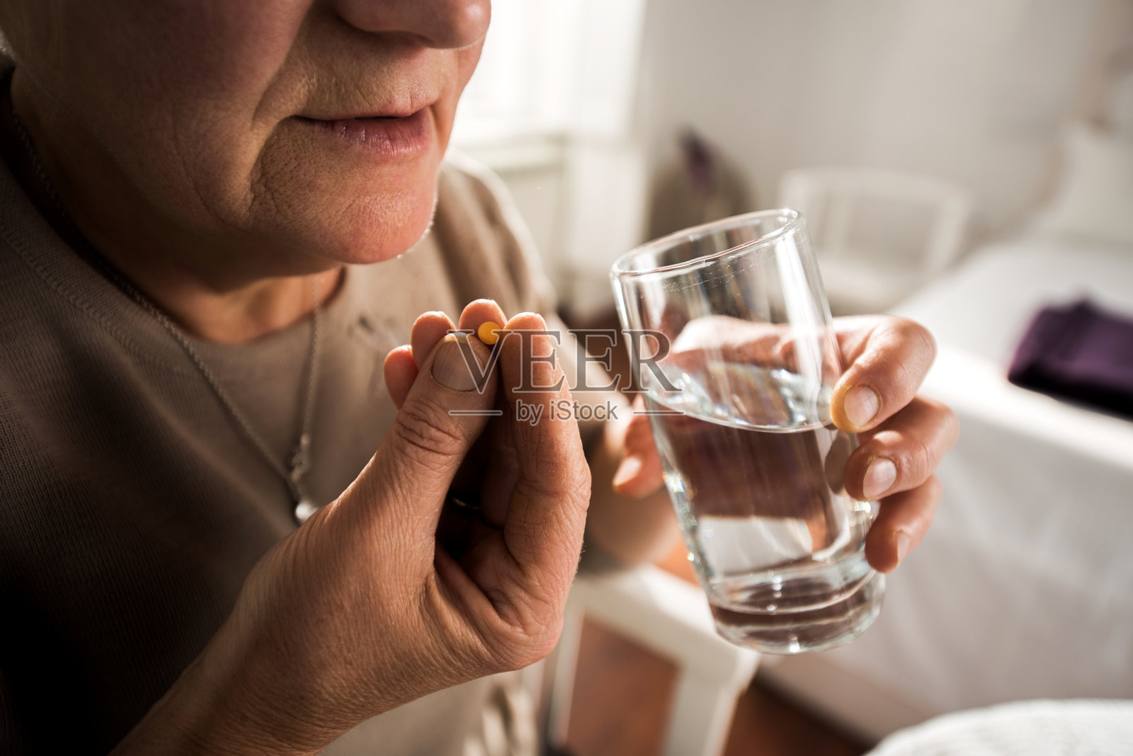 近距离观察一个面目全非的女人喝水吃药。照片摄影图片