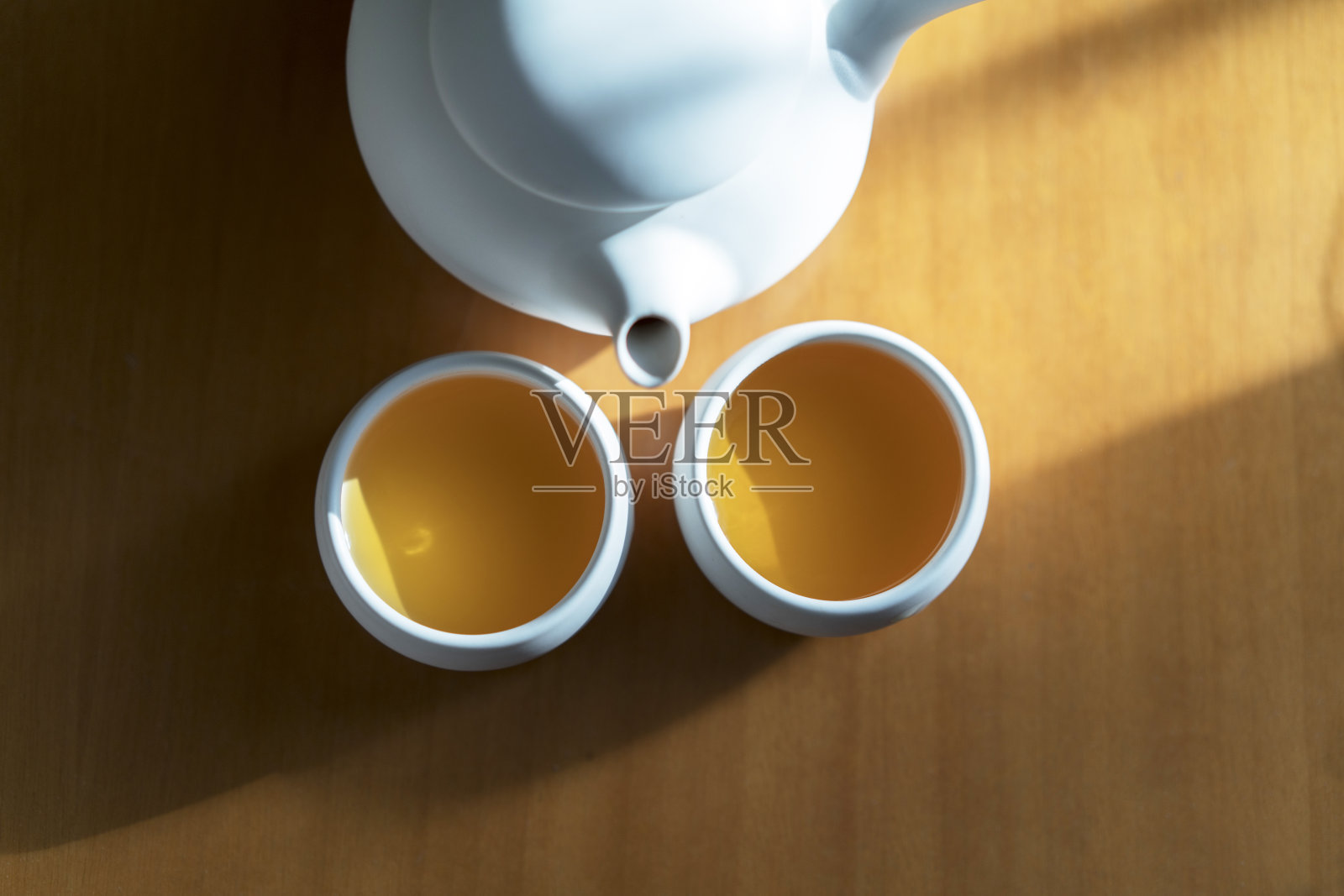 陶器茶壶和杯子在阳光下的桌子上照片摄影图片