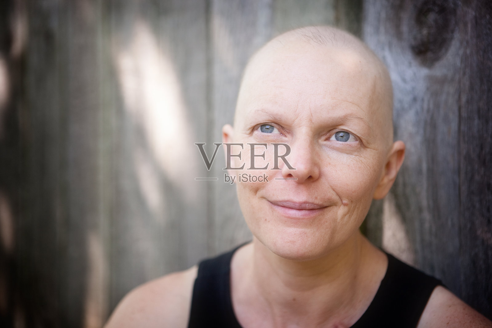 一名在户外与乳腺癌作斗争的秃顶妇女望着镜头。照片摄影图片