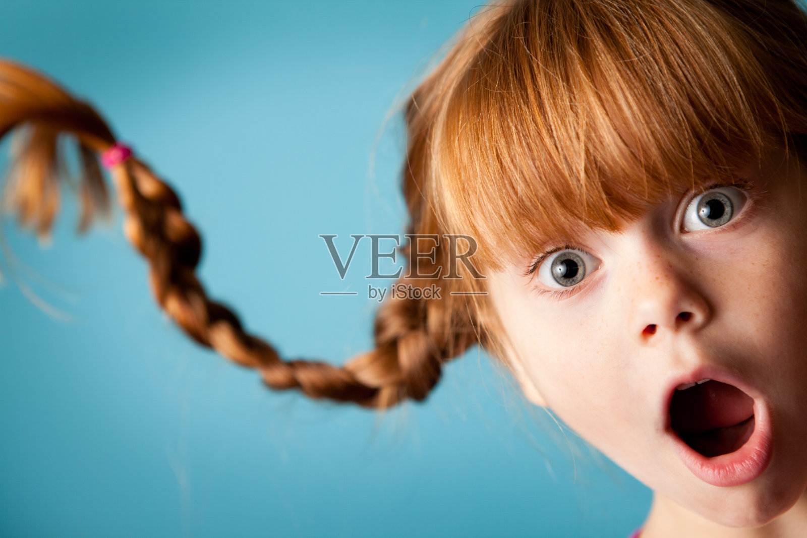 红发女孩向上梳着辫子，看起来很惊讶照片摄影图片