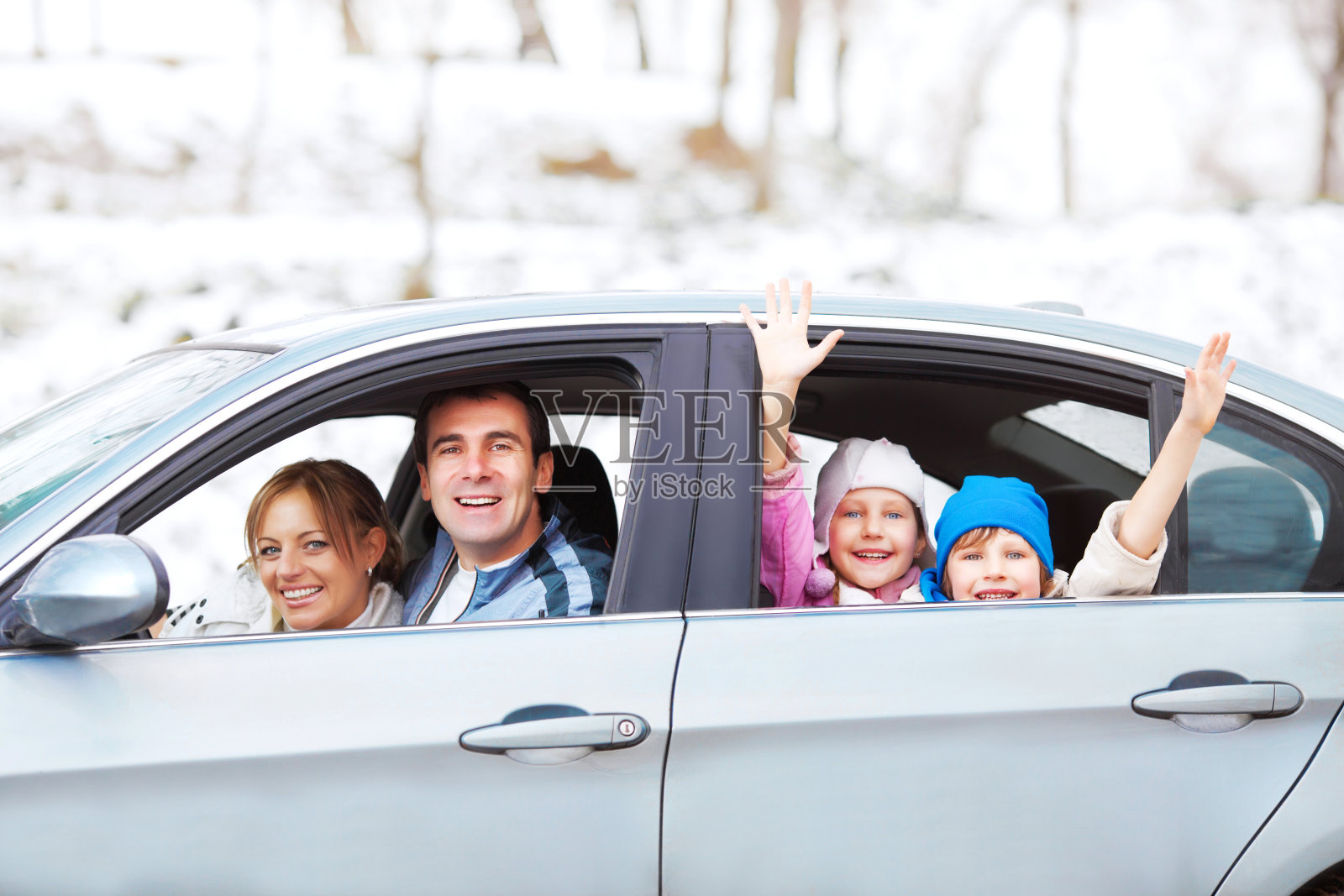 一个幸福的家庭坐在一辆车里，背景是雪景照片摄影图片