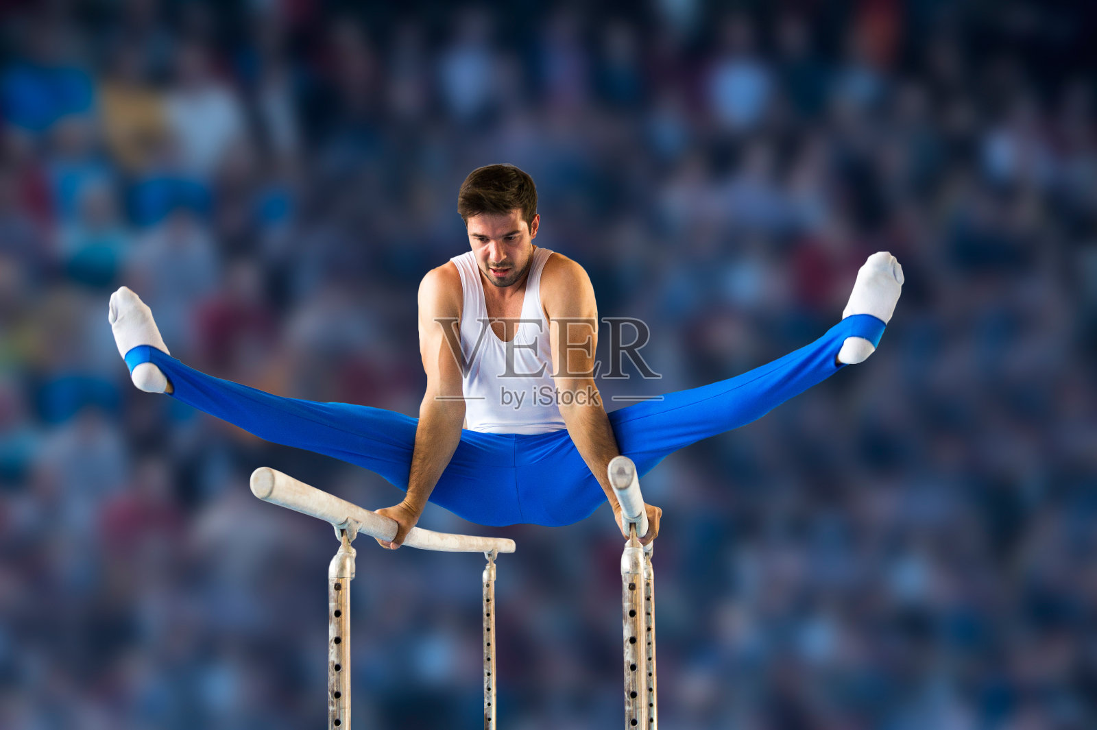 男子体操运动员在双杠上表演常规动作照片摄影图片