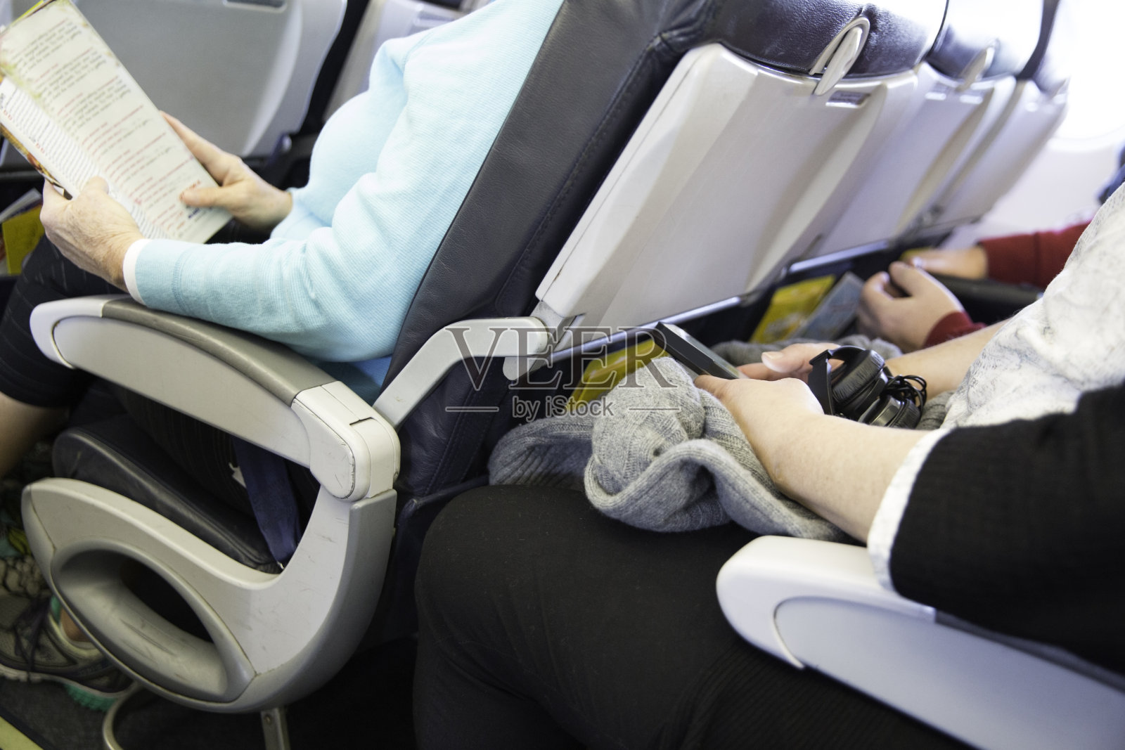 坐在飞机上的乘客在他们的座位上是狭窄的照片摄影图片