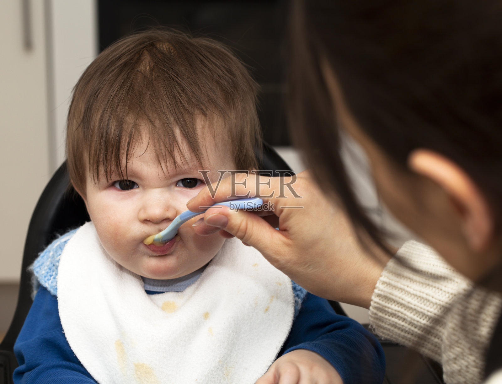 婴儿被用勺子喂粥。照片摄影图片